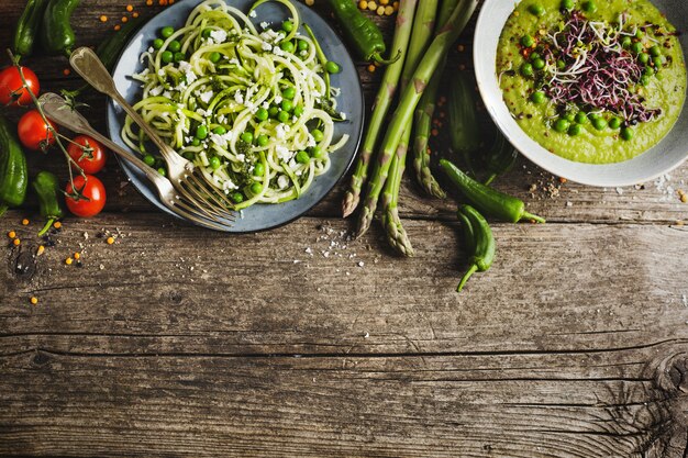 Healthy green pea soup and zucchini noodles on wooden table copyspace