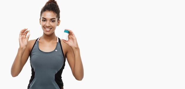 Healthy and healthcare concept portrait of beautiful sporty african american holding bottle of supp