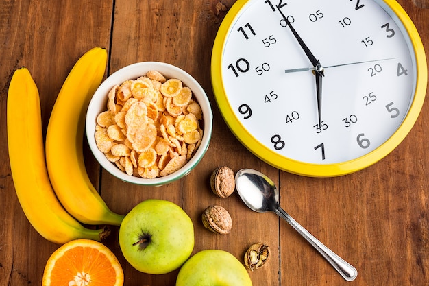 Foto gratuita sana colazione fatta in casa di muesli, mele, frutta fresca e noci con orologio