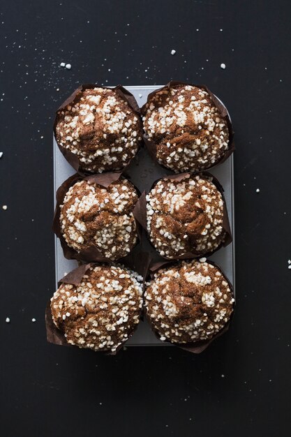 Healthy homemade blueberry muffins on tray against black background