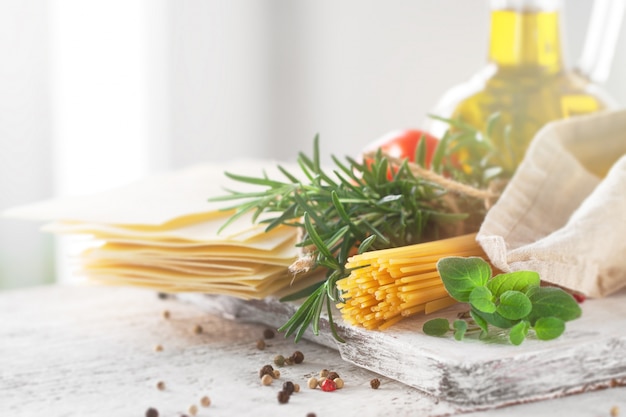 Free photo healthy ingredients on a kitchen table - spaghetti, olive oil, t