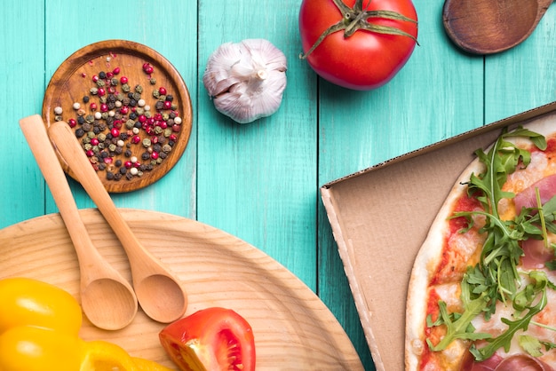 Healthy ingredients on wooden textured surface with vegetables and delicious pizza