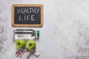 Foto gratuita composizione di vita sano con le mele, ardesia e una bottiglia d'acqua