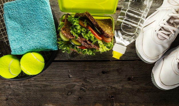 Healthy Life Sport Concept. Sneakers with Lunch Box, Towel and Bottle of Water on Wooden Background. Copy Space.