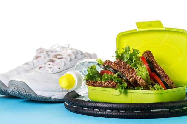 Healthy Life Sport Concept. Sneakers with Tennis Balls, Towel, Apples, Healthy Sandwich and Bottle of Water on Bright Background. Copy Space.