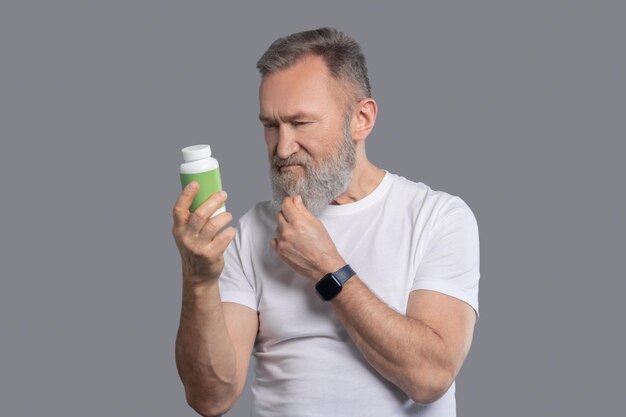 Healthy lifestyle. A bearded man holding a jar with vitamins
