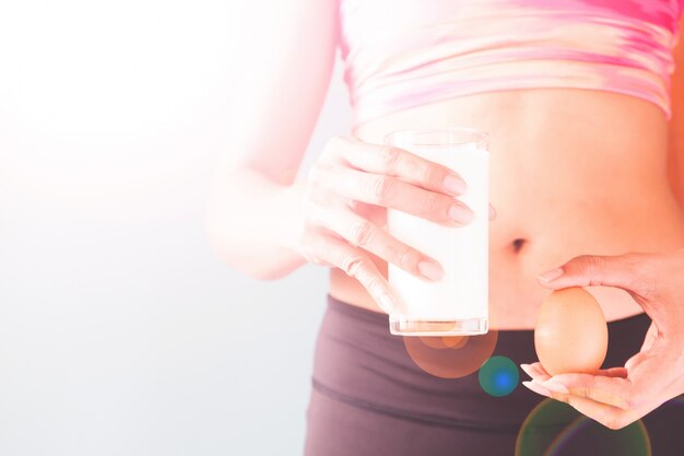 Healthy lifestyle concept, Diet and fitness, Fitness female holding glass of milk and egg with copy space