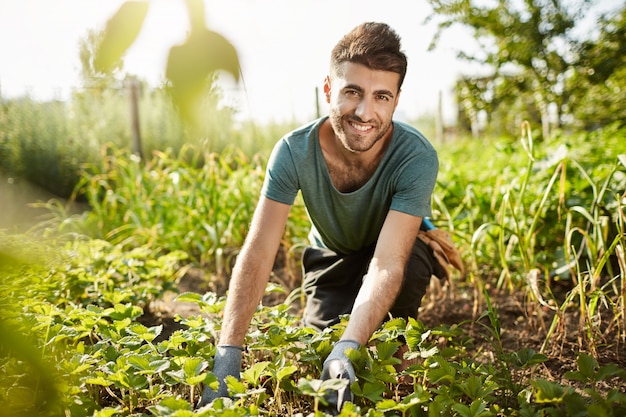 Здоровый образ жизни. Сельская жизнь. Крупным планом портрет молодого привлекательного бородатого кавказского фермера, проводящего утро в саду возле дома, сбора урожая
