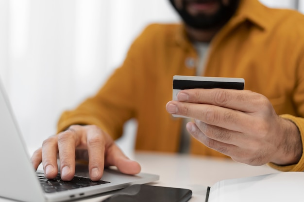 Person typing on laptop while holding his credit card
