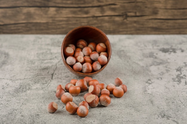 Healthy macadamia nuts in shell on a stone background. 