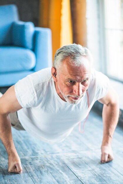 Healthy man doing pushup on hardwood floor at home