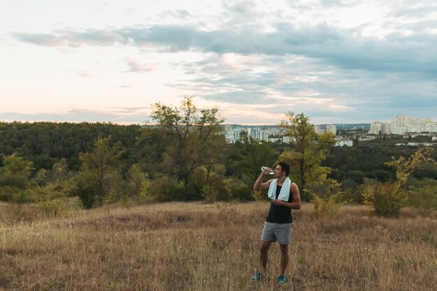 Healthy man drinking water on nature while resting