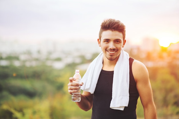 Healthy man drinking water on nature while resting