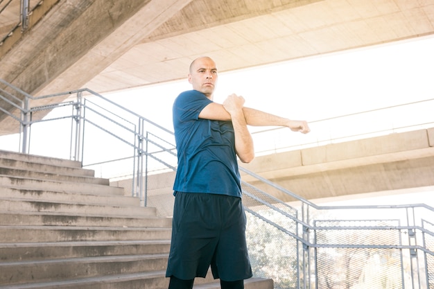 Healthy man standing on staircase stretching his hand