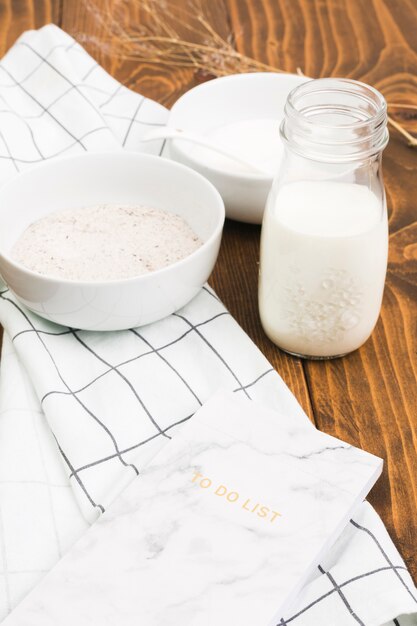 Healthy milk bottle; flour bowl and to do list over wooden panel