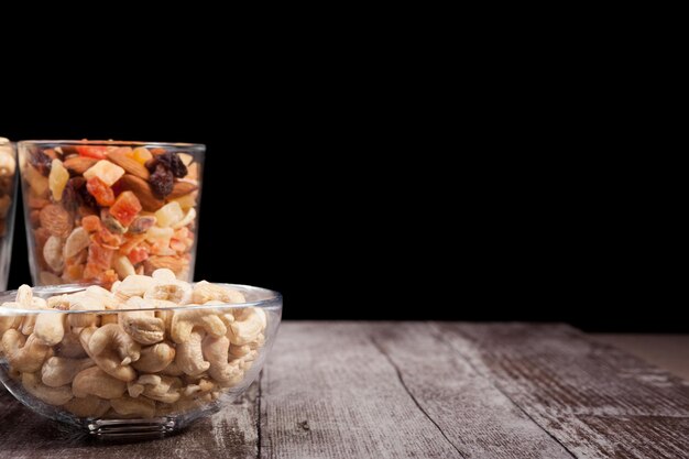 Healthy mix of dried nuts and sweets in was glass on wooden background in studio photo