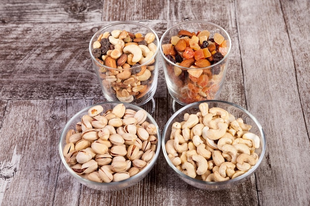 Un sano mix di noci e dolci secchi in vetro su sfondo di legno in studio fotografico