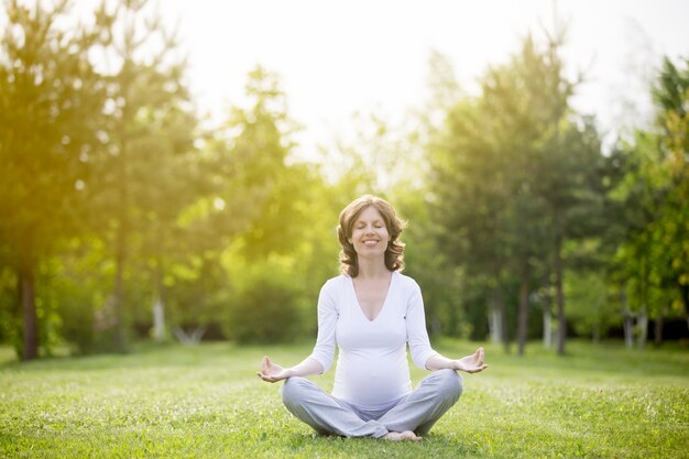 Healthy pregnant woman meditating outdoors with closed eyes