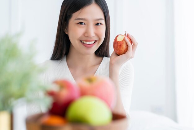 건강한 예쁜 아시아 여성의 행복은 빨간색 신선한 사과 과일 체중 감량 iedeas 개념 화이트 룸 인테리어 배경으로 먹고 사랑을 즐깁니다.