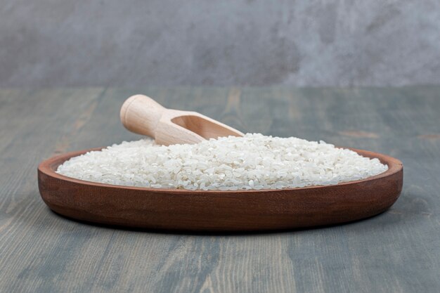 Healthy raw rice with wooden spoon on a wooden table