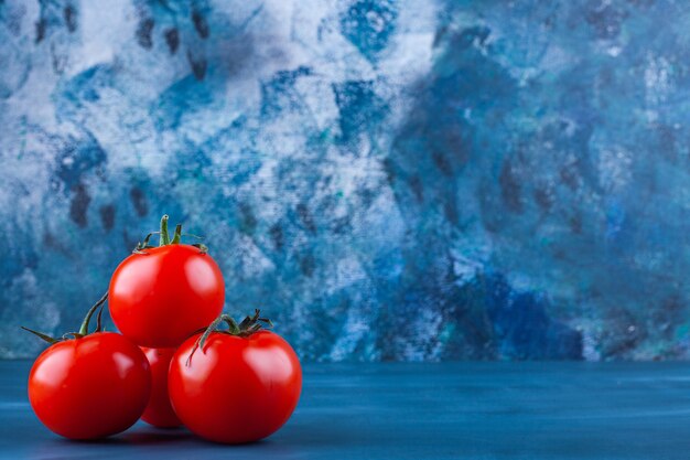 Healthy red fresh tomatoes placed on blue surface