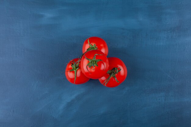 Healthy red fresh tomatoes placed on blue surface.