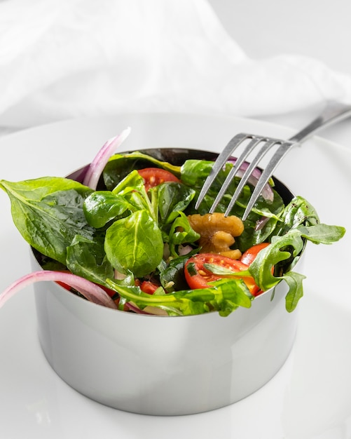 Healthy salad in metal round form with a fork