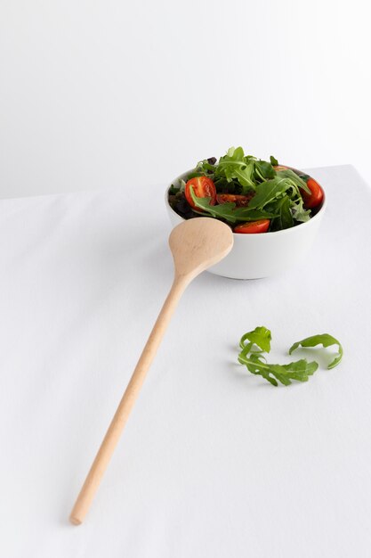 Здоровый салат в белой миске на белом столе