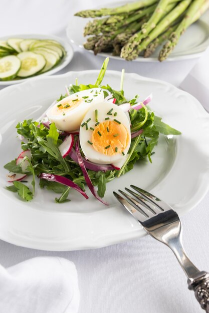 Healthy salad with egg on a white plate composition