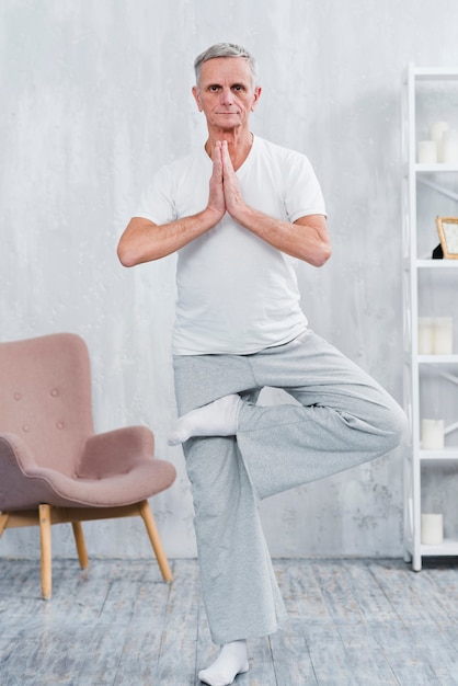 Yoga di pratica dell'uomo senior in buona salute che esamina macchina fotografica