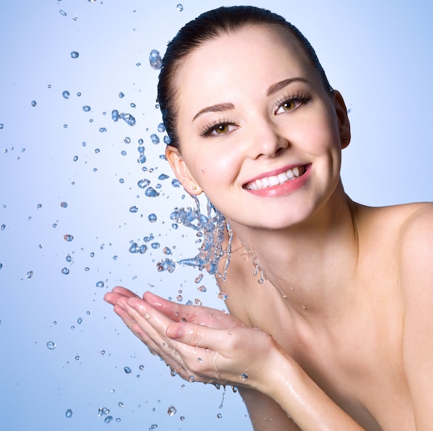 Бесплатное фото Здоровая улыбающаяся женщина, умывающая лицо чистой водой