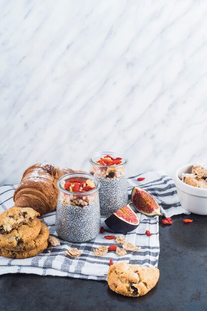 Healthy smoothie with backed cookies and croissant on napkin against marble textured background