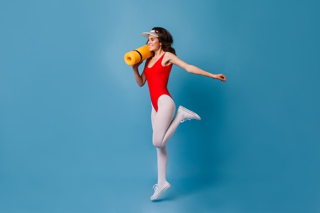 Healthy strong young woman of 80s doing sports on blue wall