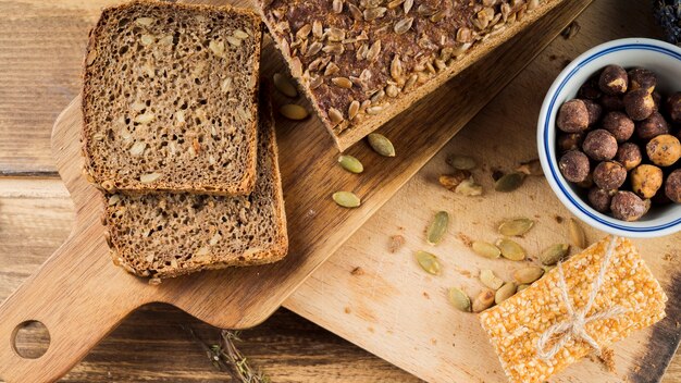 Healthy sunflower seed bread and hazelnut bowl with protein bar on chopping board