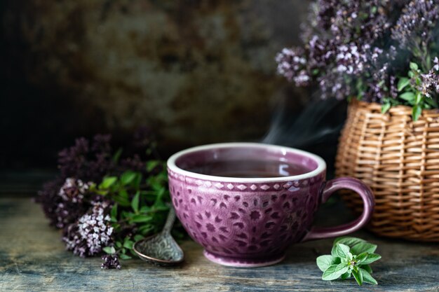 木製の背景に美しいマグカップでオレガノの花から健康茶。コピースペース