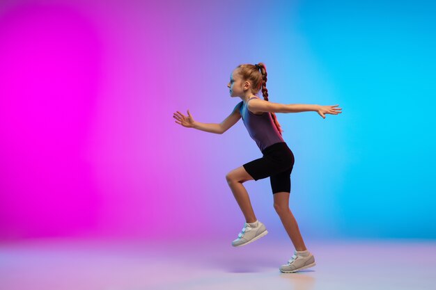 건강한. 십 대 소녀, 프로 러너, 행동에 조깅, 네온 불빛에 그라데이션 핑크 블루 배경에 고립 된 모션. 스포츠, 운동, 에너지 및 역동적이고 건강한 라이프 스타일의 개념.