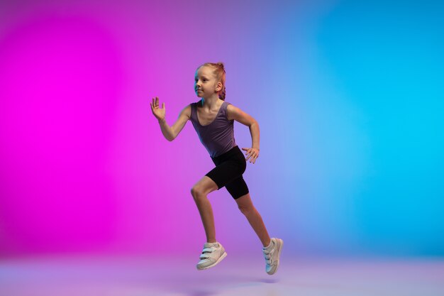 건강한. 십 대 소녀, 프로 러너, 행동에 조깅, 네온 불빛에 그라데이션 핑크 블루 배경에 고립 된 모션. 스포츠, 운동, 에너지 및 역동적이고 건강한 라이프 스타일의 개념.