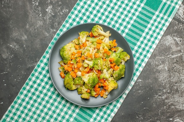 Здоровый овощной салат на зеленом полосатом полотенце на сером столе