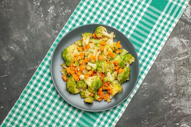 Healthy vegetable salad on green stripped towel on gray table