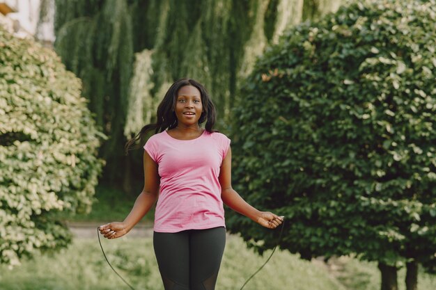 Healthy young african woman outdoors in morning. Girl with a rope.