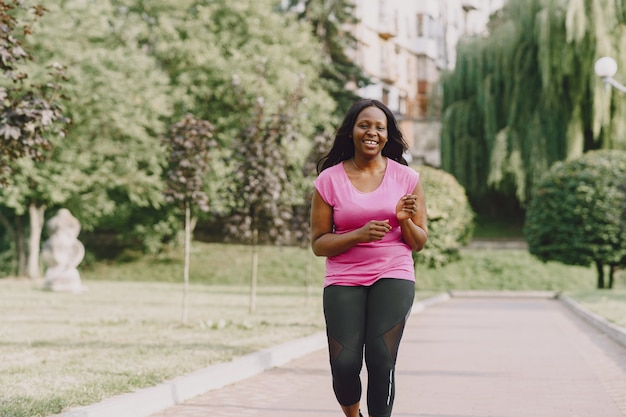 Healthy young african woman outdoors in morning. Woman in pink t-shirt.