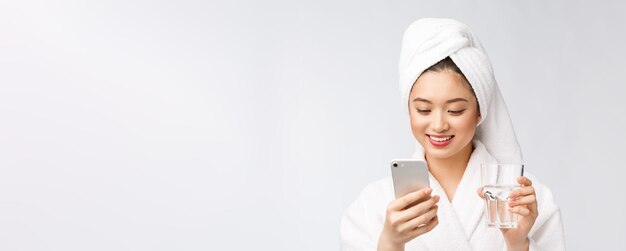 건강 한 젊은 아름 다운 여자 식수 아름다움 얼굴 흰색 배경 위에 절연 휴대 전화를 들고 자연 화장