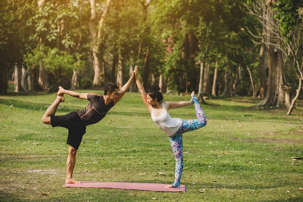 Healthy young couple doing yoga in the park