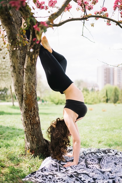 Healthy young woman doing handstand exercise in garden