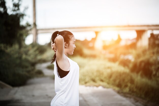 Healthy young woman warming up outdoors workout before training session at the park.