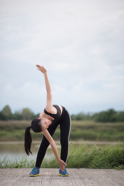 Healthy young woman warming up outdoors workout before training session at the park.