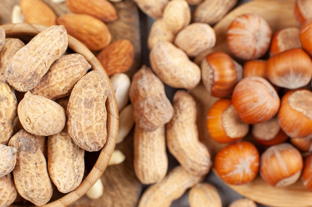 A heap of almonds, peanuts and hazelnuts in bowls and on wooden board. High quality photo