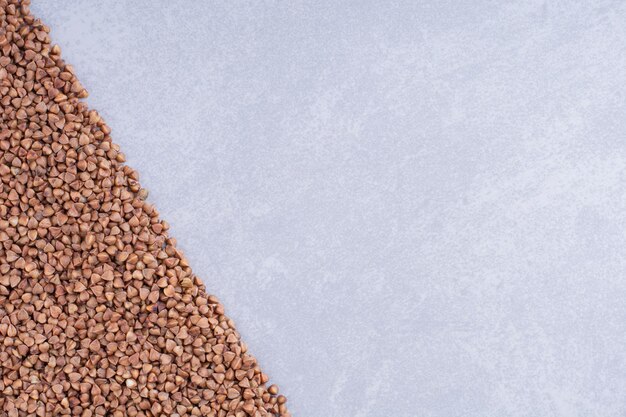 Heap of buckwheat arranged in a triangular shape on marble surface