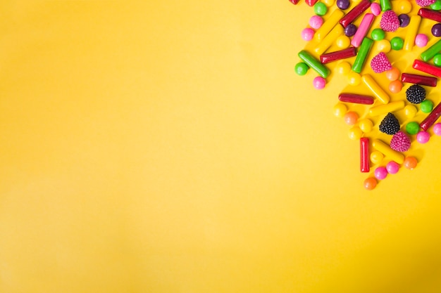 Heap of colorful sweets on yellow background