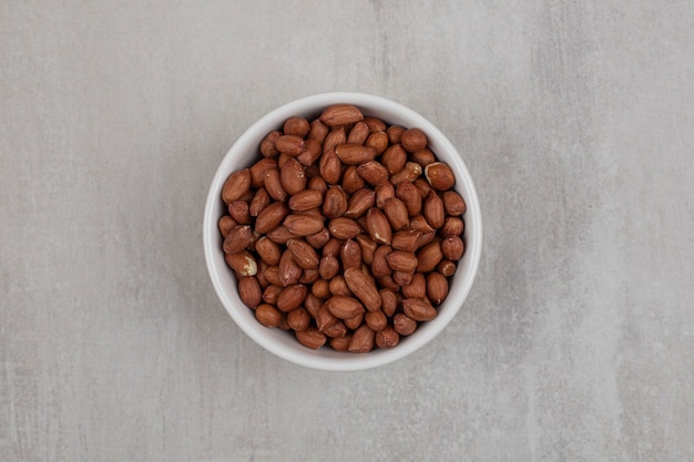 Free photo heap of fresh peanuts in white bowl.